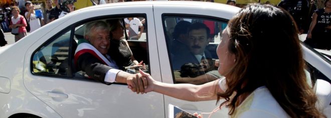 Женщина пожимает руку новому президенту Мексики Андресу Мануэлю Лопесу Обрадору, когда он едет на своей машине по направлению к Национальному дворцу в Мехико