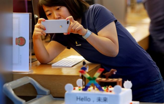 Сотрудник Apple фотографирует, когда новый iPhone X начинает продаваться в Apple Store в Пекине