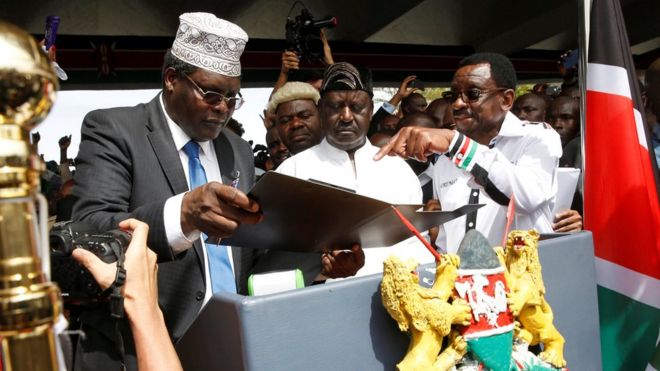 Лидер оппозиции Кении Раила Одинга из Национального супер-альянса (НАСА) получает помощь от адвоката Мигуны Мигуны и Джеймса Оренго, поскольку он принимает символическую президентскую присягу перед своими сторонниками в Найроби, Кения, 30 января 2018 года.