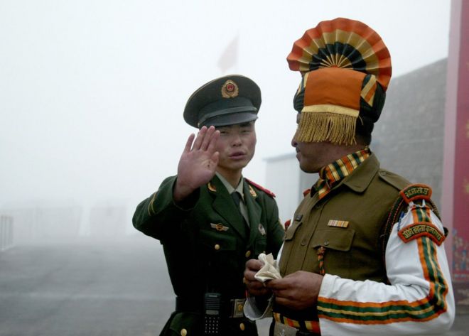 На этой фотографии, сделанной 10 июля 2008 года, китайский солдат показывает, как он стоит возле индийского солдата на китайской стороне древнего пограничного перехода Натху Ла между Индией и Китаем