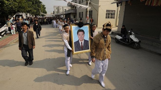 Сын Сюэ Цзиньбо (портрет), 42-летний деревенский лидер, который умер под стражей в полиции, Сюэ Цзинди (справа) и местные жители присутствуют на похоронной церемонии в рыбацкой деревне Укань в южной провинции Гуандун 16 декабря 2011 года.