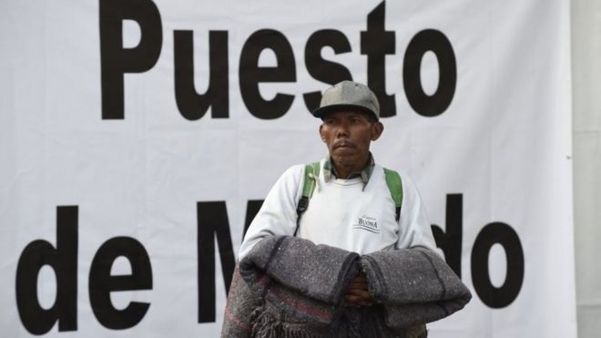Мигрант держит одеяла, когда он осматривает стадион в Мехико, где он ищет убежище