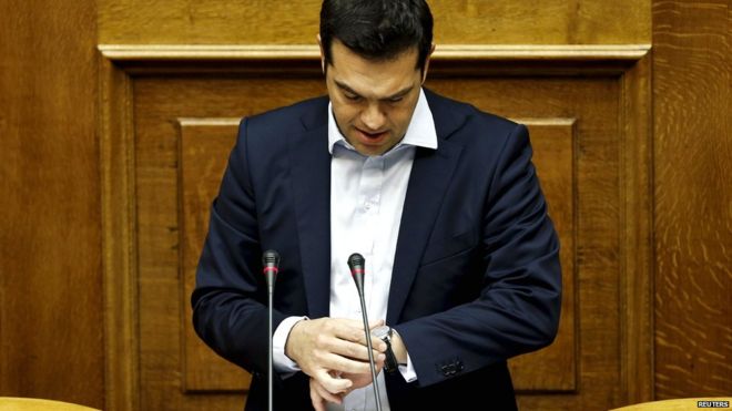 Премьер-министр Греции Алексис Ципрас смотрит на часы, выступая на парламентской сессии в Афинах 28 июня 2015 года