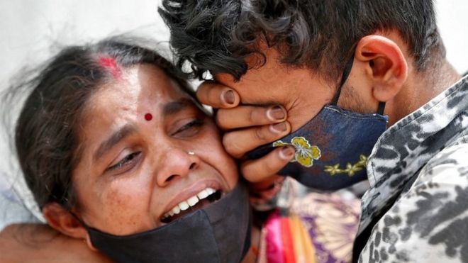 A woman mourns with her son after her husband died due to the coronavirus disease (COVID-19) outside a mortuary of a COVID-19 hospital in Ahmedabad, India, April 20, 2021