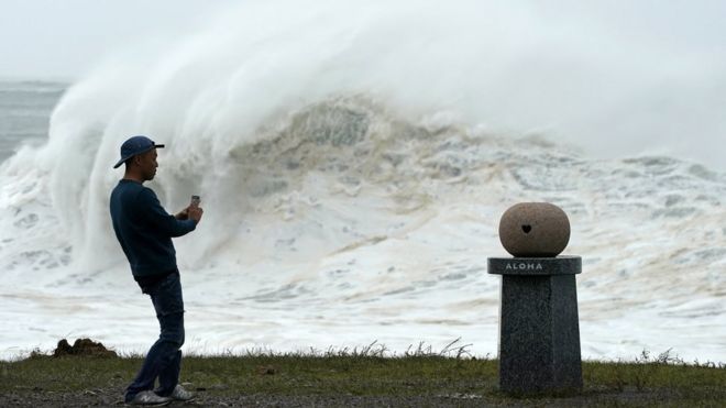 Un joven toma fotos de las altas olas generadas por el tifón Hagibis en la costa este de Japón.