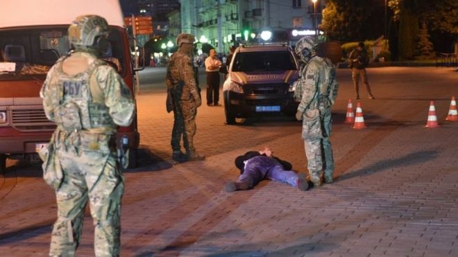 Security forces stand over detained gunman