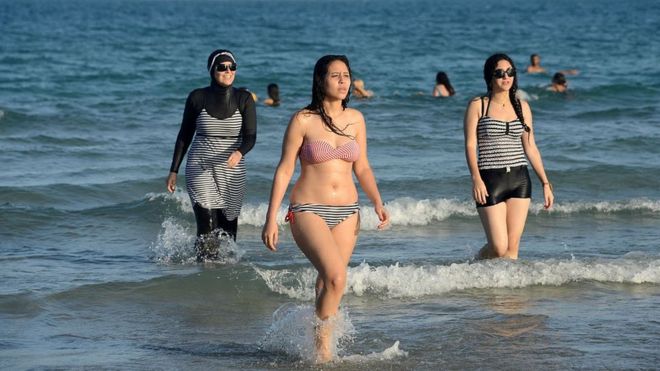 Una mujer en bikini se baña en una playa de Túnez junto a una mujer con burkini.