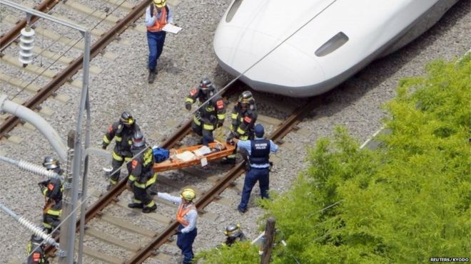 Пассажира на носилках несут спасатели из сверхскоростного пассажирского экспресса Синкансэн после того, как он сделал аварийную остановку в Одаваре, к югу от Токио, на этом снимке с воздуха, снятом Киодо 30 июня 2015 года.