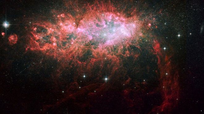 Красно-розовое пыльное облако с семейством ярких звезд в центре