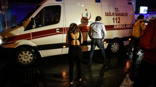 Женщина реагирует рядом с машиной скорой помощи возле места нападения в Стамбуле, раннее воскресенье, 1 января,