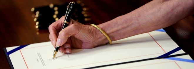 Спикер Палаты представителей Нэнси Пелоси (D-CA) подписывает закон во время церемонии регистрации, прежде чем отправить его в США.