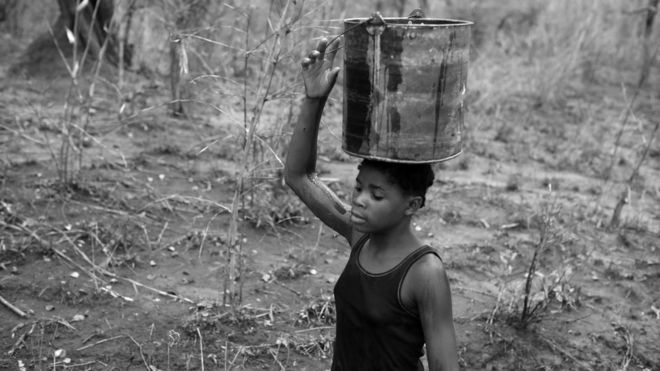 Josefina carries water home from the Rio Naranja in a bucket.