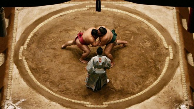 Борцы сумо Миябияма и Такэказе из Японии борются друг с другом в середине ринга во время чемпионата Гранд Сумо