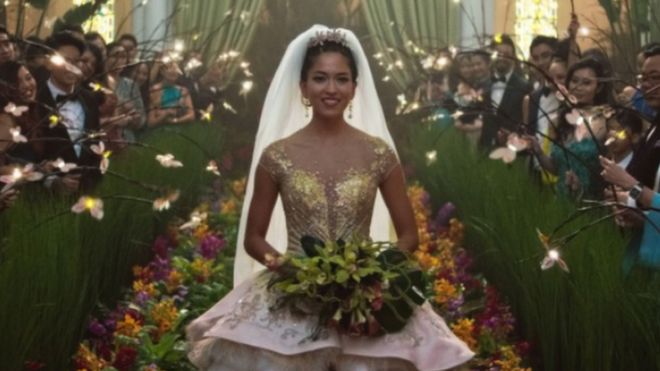 Movie still from Crazy Rich Asians showing Sonoya Mizuno walking down the aisle in a wedding dress
