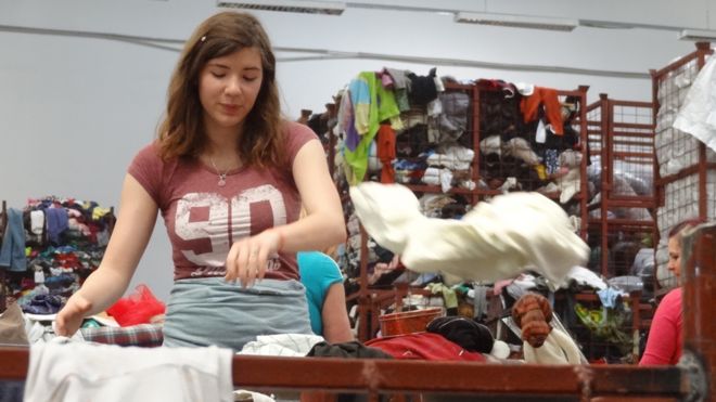 Женщина сортирует одежду на складе