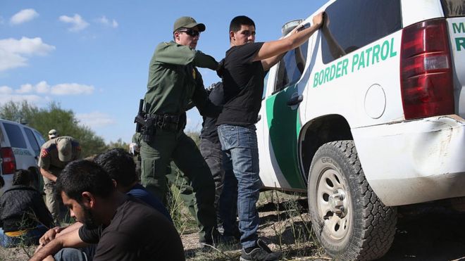 Офицер пограничной службы США обыскивает незарегистрированного иммигранта после того, как он незаконно пересек границу США и Мексики