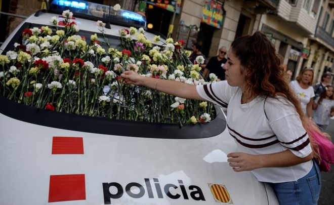 Женщина демонстрирует цветок на лобовом стекле автомобиля каталонской полиции, известного как Моссос д'Эсквадра, во время митинга за референдум в Барселоне 24 сентября 2017 года.