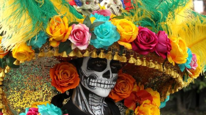 A woman with skeleton make-up has a large floral hat on