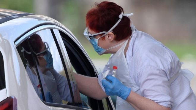 Медицинский персонал тестирует людей в центре тестирования на коронавирус на автостоянке тематического парка в Чессингтоне