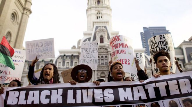 Протестующие проходят мимо здания муниципалитета во время демонстрации по поводу смерти Фредди Грея возле здания муниципалитета 30 апреля в Филадельфии, штат Пенсильвания.