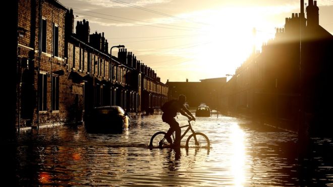 Велосипедист проезжает через паводковые воды