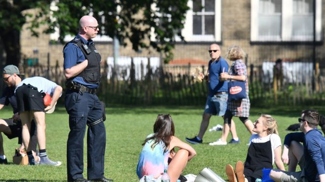 Police speak to people gathering in a park in England