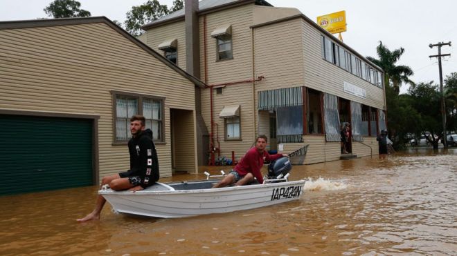 Жители используют лодку, чтобы путешествовать по улице в Billinudgel, Новый Южный Уэльс.
