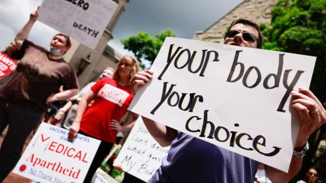 Protesters holding placards gather at Indiana University's Sample Gates during the demonstration. Anti-vaxxers and anti-maskers gathered at Indiana University's Sample Gates to protest against mandatory Covid vaccinations
