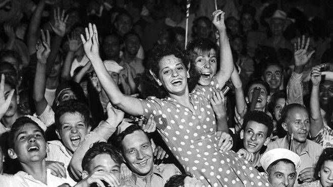 A crowd celebrates and holds a woman in the air