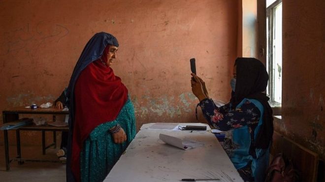 An Independent Election Commission officia scans a voter's face with a biometric device at a polling station in Mazar-i-Sharif on 28 September 2019