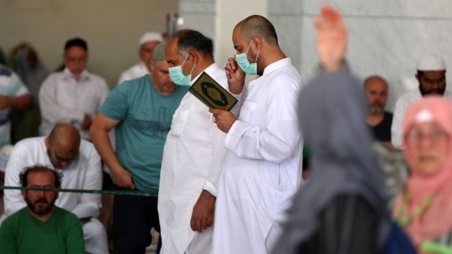 Прихожане, некоторые из них в защитных масках, принимают участие в пятничной молитве перед Большой мечетью Мекки