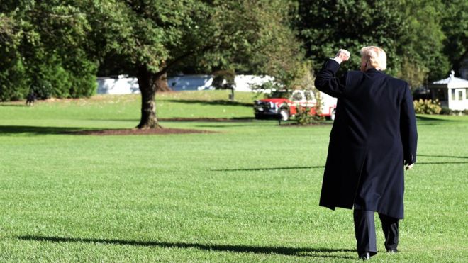 Президент США Дональд Трамп поднимает кулак, когда идет по южной лужайке перед посадкой в ??Marine One в Белом доме, 13 октября 2018 года