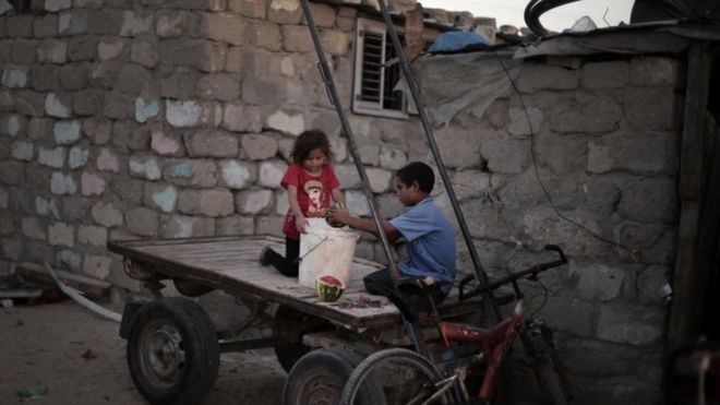 Палестинские дети готовят еду для лошади, когда сидят на телеге рядом со своим домом в трущобах Эль-Зохор на окраине лагеря беженцев Хан-Юнис в южной части сектора Газа