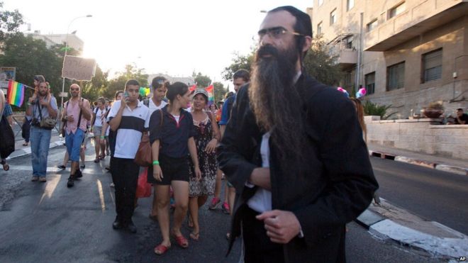 Ультраортодоксальный еврей Ишай Шлиссель проходит через парад гей-парадов и вот-вот вытащит нож из-под пальто и начнет наносить удар людям в Иерусалиме, четверг, 30 июля 2015 года.