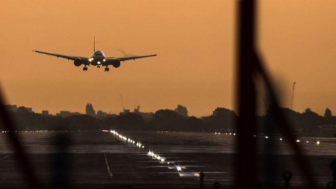 Пассажирский самолет готовится к посадке во время восхода солнца в лондонском аэропорту Хитроу