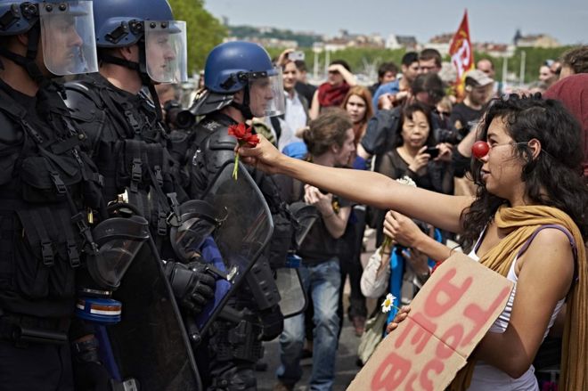 Протестующий сталкивается с полицией с букетом цветов в Лионе, 26 мая