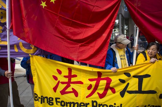 Практикующие Фалуньгун, которые заявляют, что религиозное движение преследуется в Китае, протестуют против визита президента Китая Си Цзиньпина, поскольку контрпротестанты закрывают свои знаки китайскими флагами в Сиэтле, штат Вашингтон, 22 сентября 2015 года