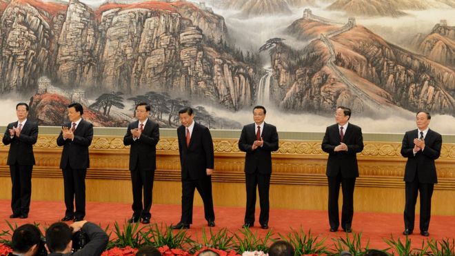 Семь мужчин в темных костюмах выходят на сцену на Конгрессе КПК в Пекине - новом постоянном комитете политбюро партии.
