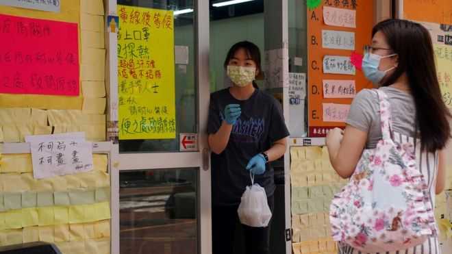 Сотрудник в маске после вспышки коронавируса (Covid-19) вручает еду на вынос покупателю у ресторана в Гонконге, Китай
