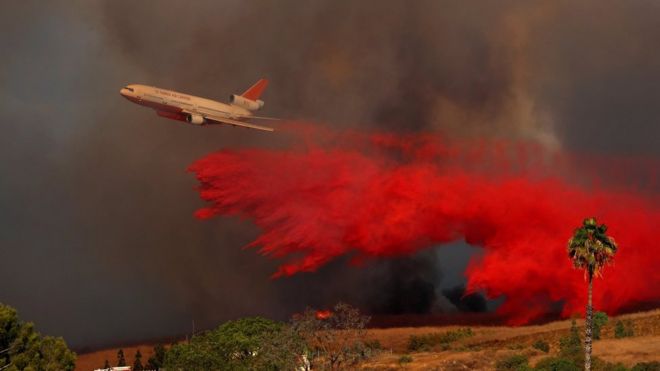 A DC-10 aircraft drops fire retardant on a wildfire in Orange, California, 9 October