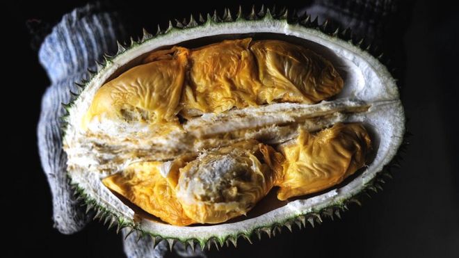 A vendor displays the cross section of a durian fruit at a roadside shop in Karak