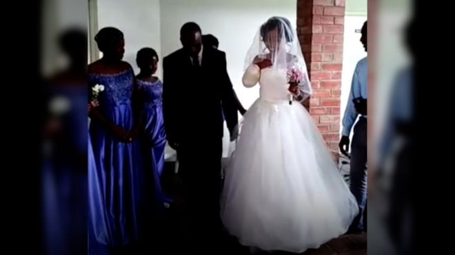 невеста, входящая в часовню рядом с отцом, с отсутствующей правой рукой и перевязанным пнем