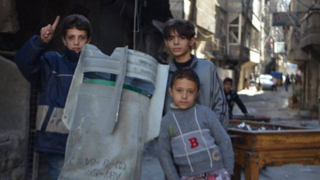 Дети позируют для фотографии рядом с неразорвавшейся бомбой