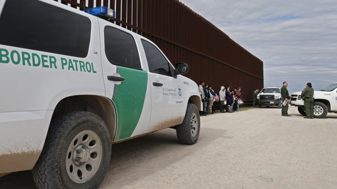 Семьи, которые пересекли границу, чтобы незаконно въехать в США, передаются агентам пограничного патруля США рядом с забором вдоль реки Рио-Гранде возле Макаллена, штат Техас, 23 января 2019 года