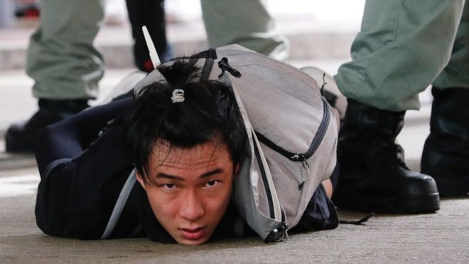 A man lies on the ground as he is detained by riot police during a march against the national security law