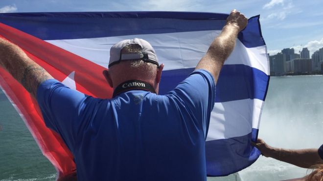 Рик Шнайдер на круизном судне, направляющемся в Гавану, машет кубинским флагом