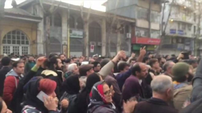 Picture shows protests gathered in a street in Rasht with their arms raised