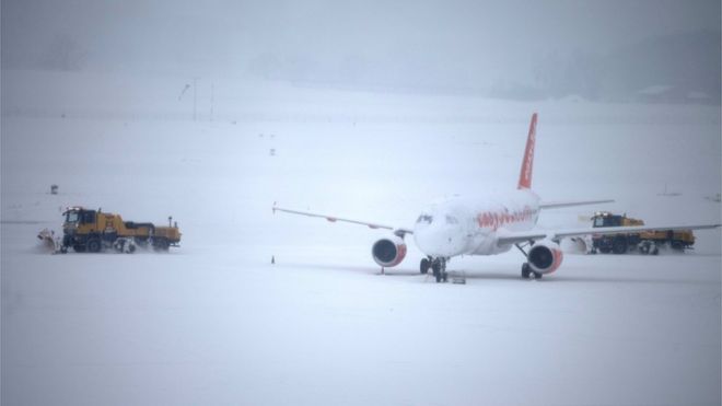 Снегоочиститель убирает снег рядом с самолетом EasyJet во время временного закрытия в аэропорту Коинтрин в Женеве, Швейцария, 1 марта 2018 года