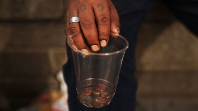Бездомный держит чашку с монетами