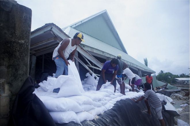Изображение людей, заполняющих мешки с морской дамбой в Кирибати